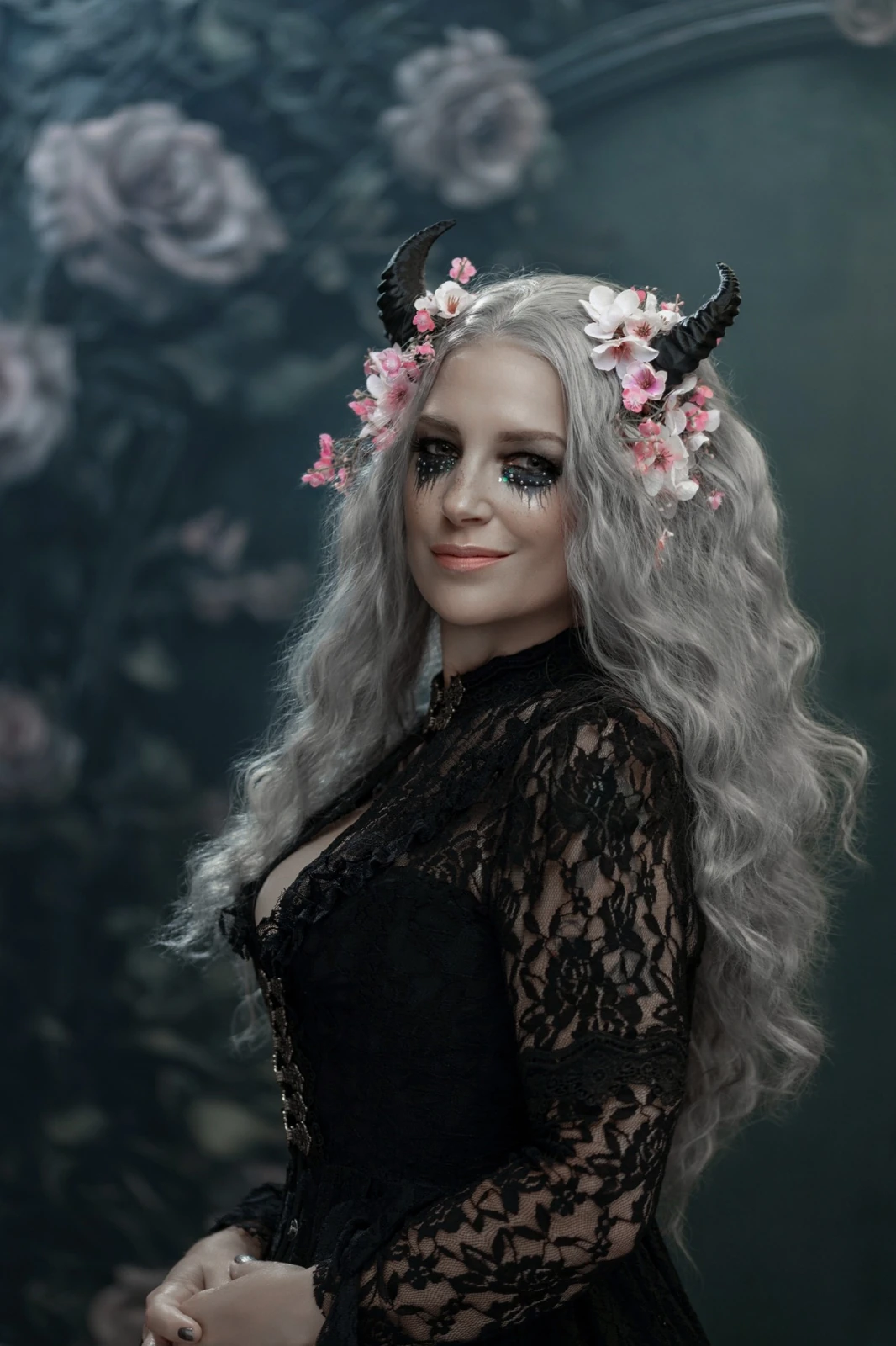 Close portrait of a silver-haired woman with a pink floral headpiece against the Victorian Gothic Frame with Flowers backdrop