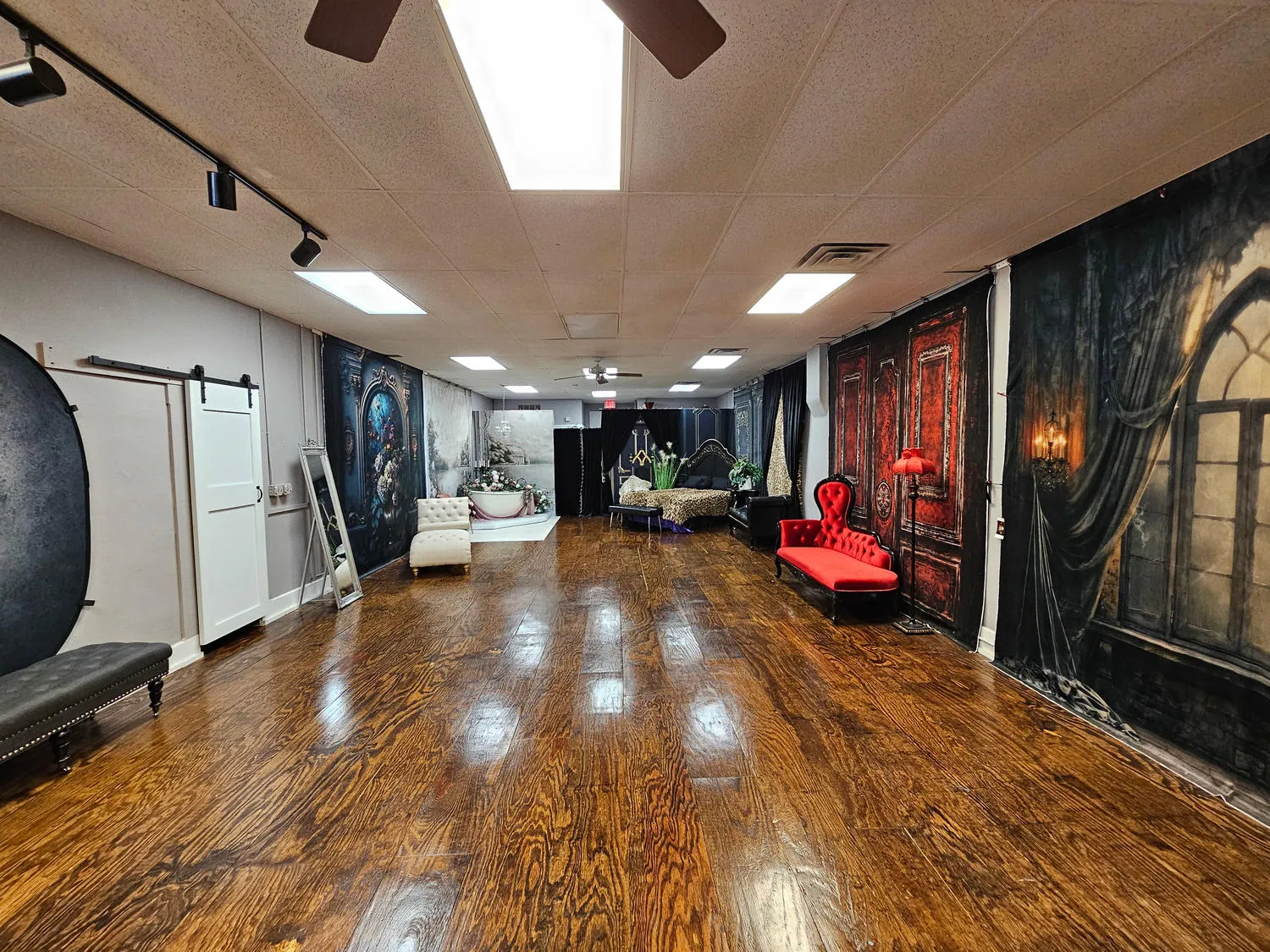 The main shooting room with open wood floors, multiple backdrops and distinctive posing furniture