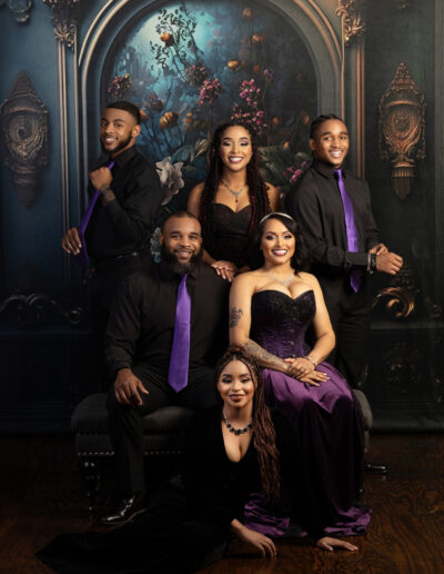Large family wearing coordinated black and purple formal clothing in a fine-art portrait.