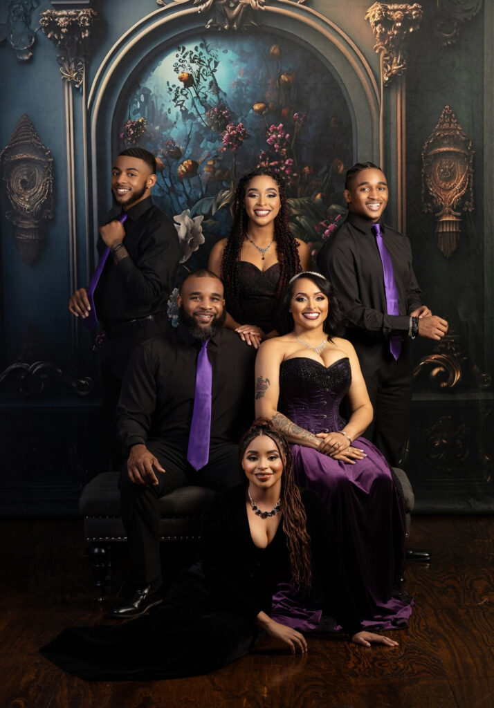 Large family wearing coordinated black and purple formal clothing in a fine-art portrait.