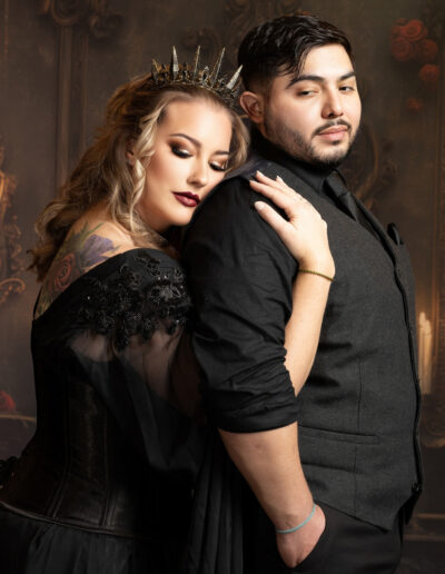 Couple dressed in black sharing a close embrace during a dramatic studio portrait.