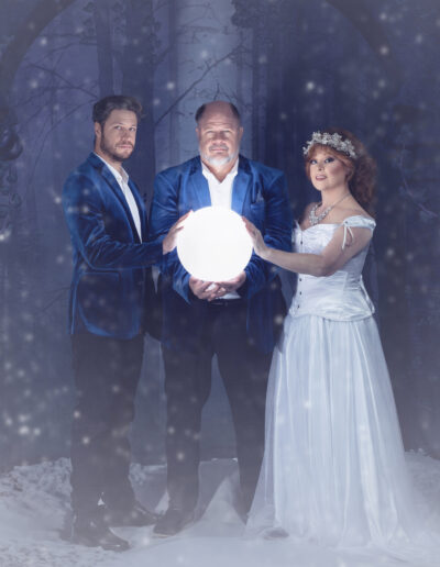 Three adults in formal fantasy attire gathered around a glowing orb.