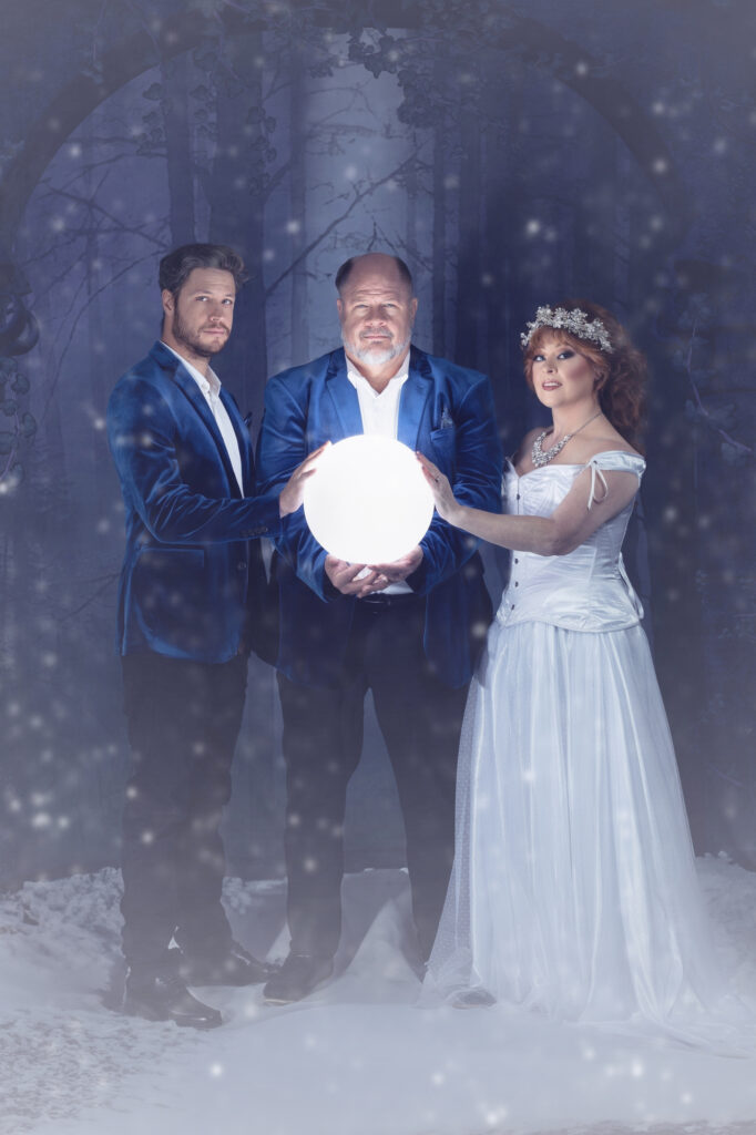 Three adults in formal fantasy attire gathered around a glowing orb.