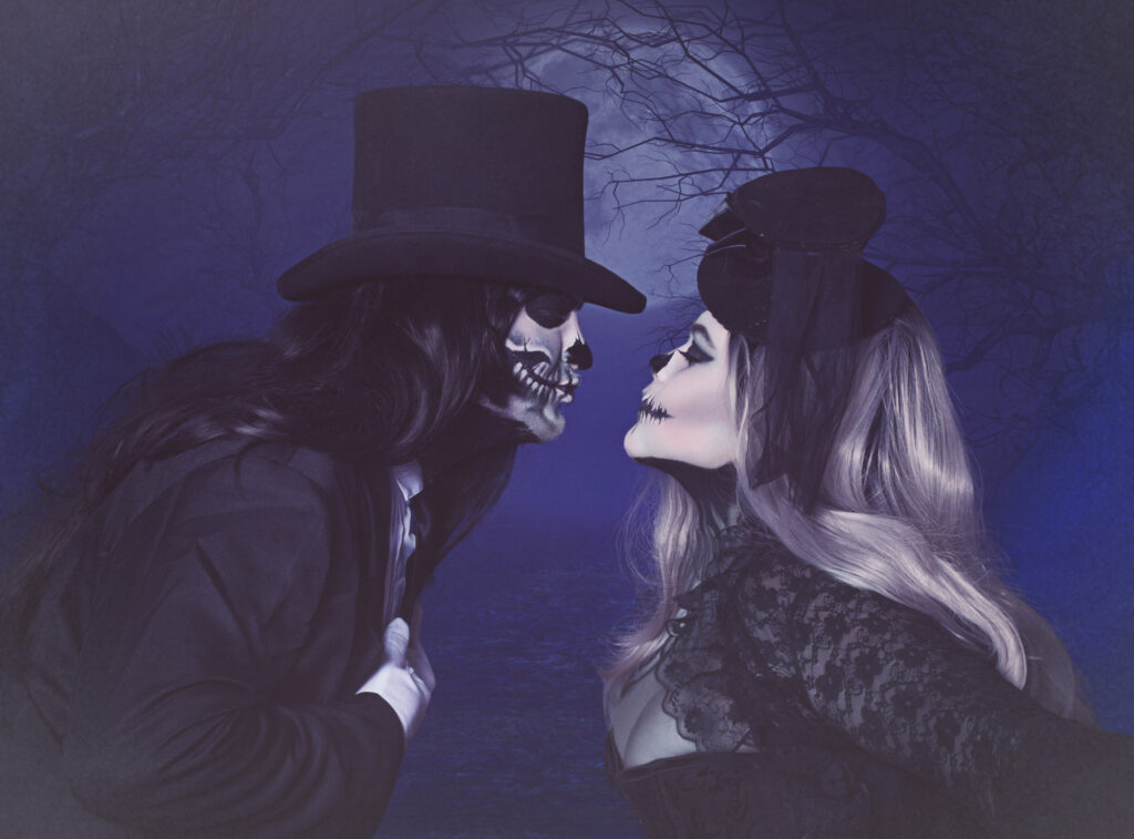 Gothic couple in tall black hats facing one another within a blue moonlit scene.