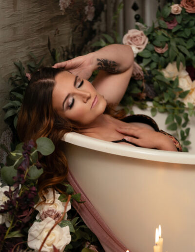 Woman reclining in a candlelit floral bathtub boudoir scene