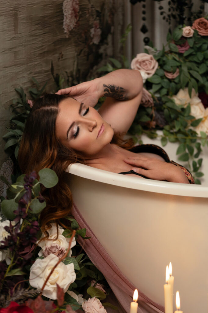 Woman reclining in a candlelit floral bathtub boudoir scene
