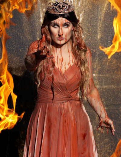 Powerful fire queen in an orange gown surrounded by flames
