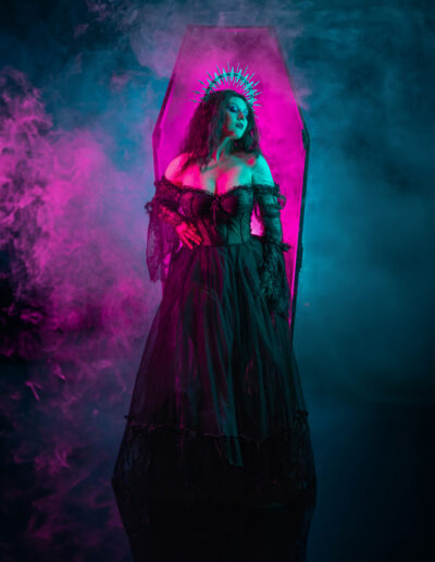 Gothic woman in a flowing black gown surrounded by colorful smoke