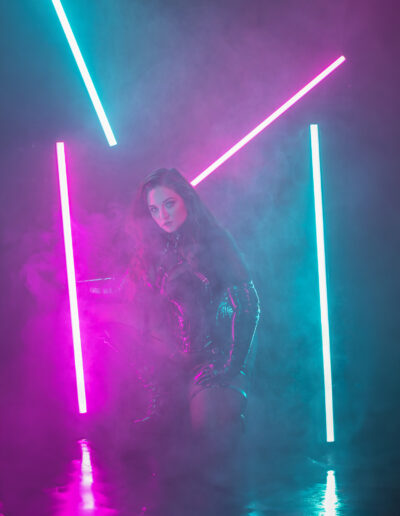 Gothic woman standing inside a tunnel of magenta and blue neon light