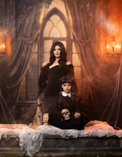 Gothic woman in black posed with a creepy Victorian doll