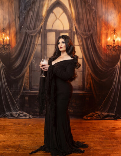 Elegant gothic woman in a black gown inside an ornate curtained room