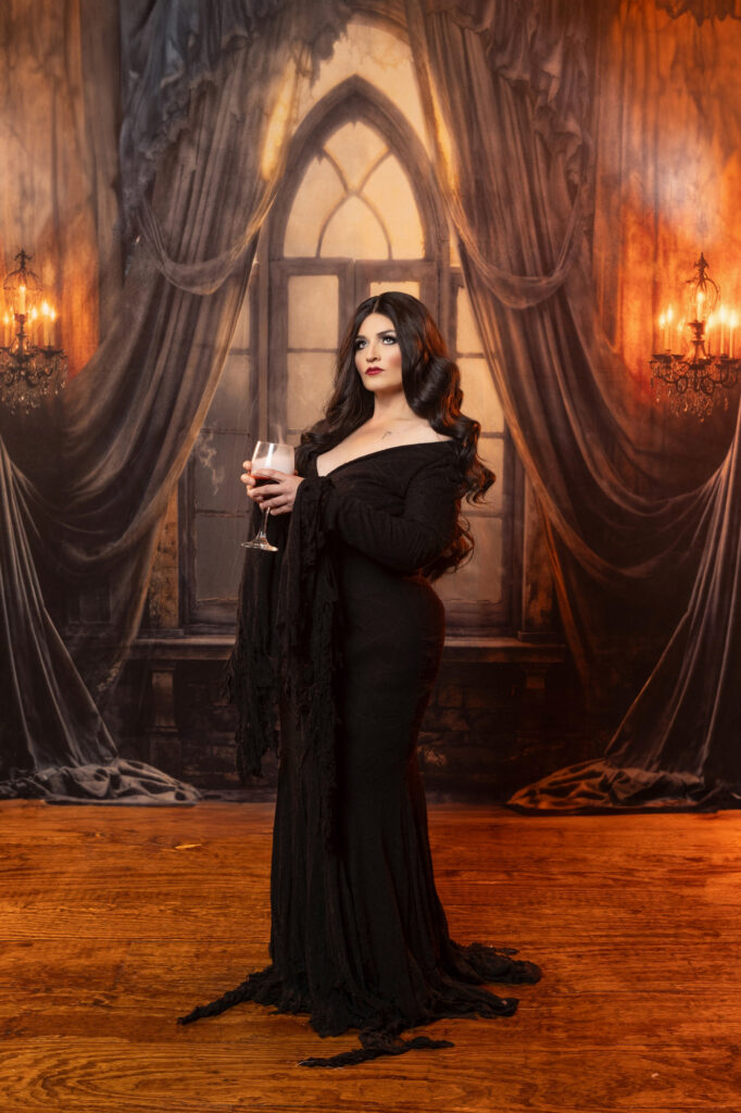 Elegant gothic woman in a black gown inside an ornate curtained room