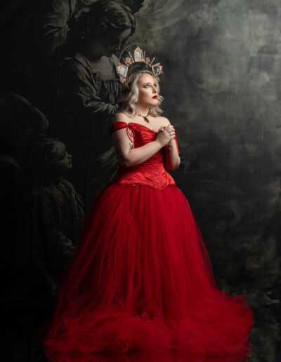 Dark romantic woman in a dramatic red gown against a painterly backdrop
