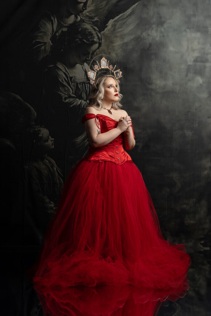 Dark romantic woman in a dramatic red gown against a painterly backdrop