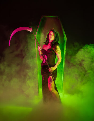Hooded gothic reaper holding a scythe amid eerie green fog