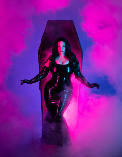 Dark gothic woman surrounded by vivid magenta and blue smoke