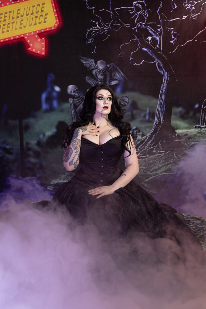 Dark-haired woman in a purple gown seated within a mystical nighttime forest.