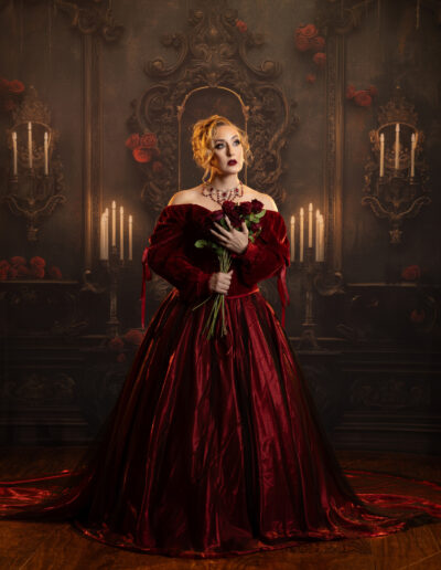 Victorian gothic woman in a red-and-black gown holding a crimson flower