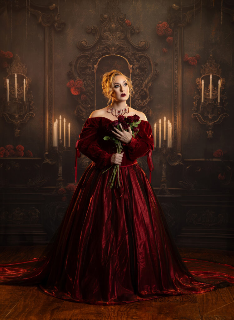 Victorian gothic woman in a red-and-black gown holding a crimson flower