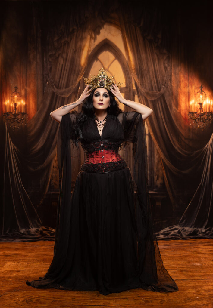 Haunted gothic woman in black inside a dramatic curtained room