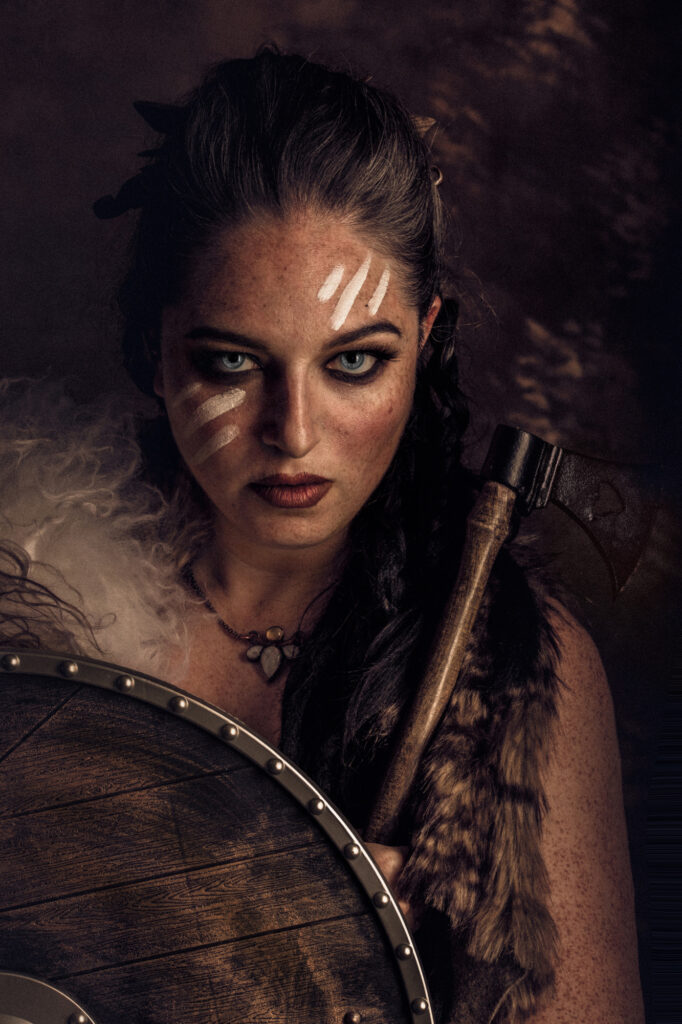 Intense fantasy warrior portrait with dark facial markings and battle-worn makeup.