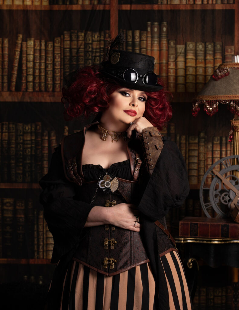 Red-haired woman in a black top hat, corset and striped skirt inside a vintage library.