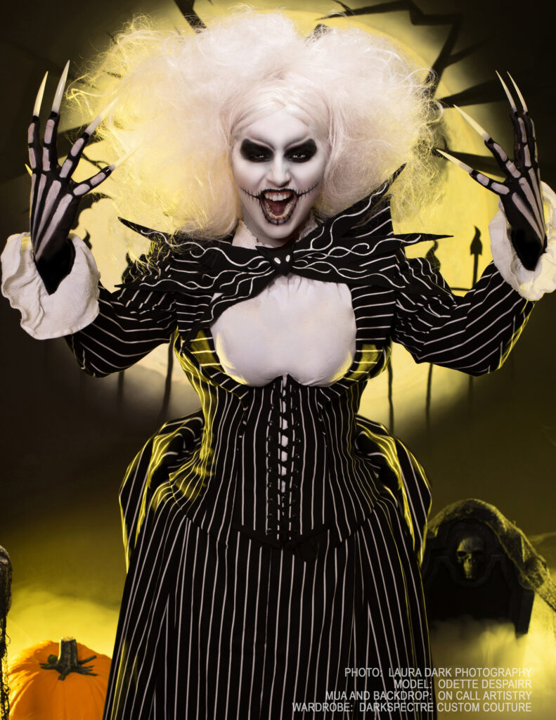White-haired skeletal fantasy character in a black striped costume surrounded by yellow light.