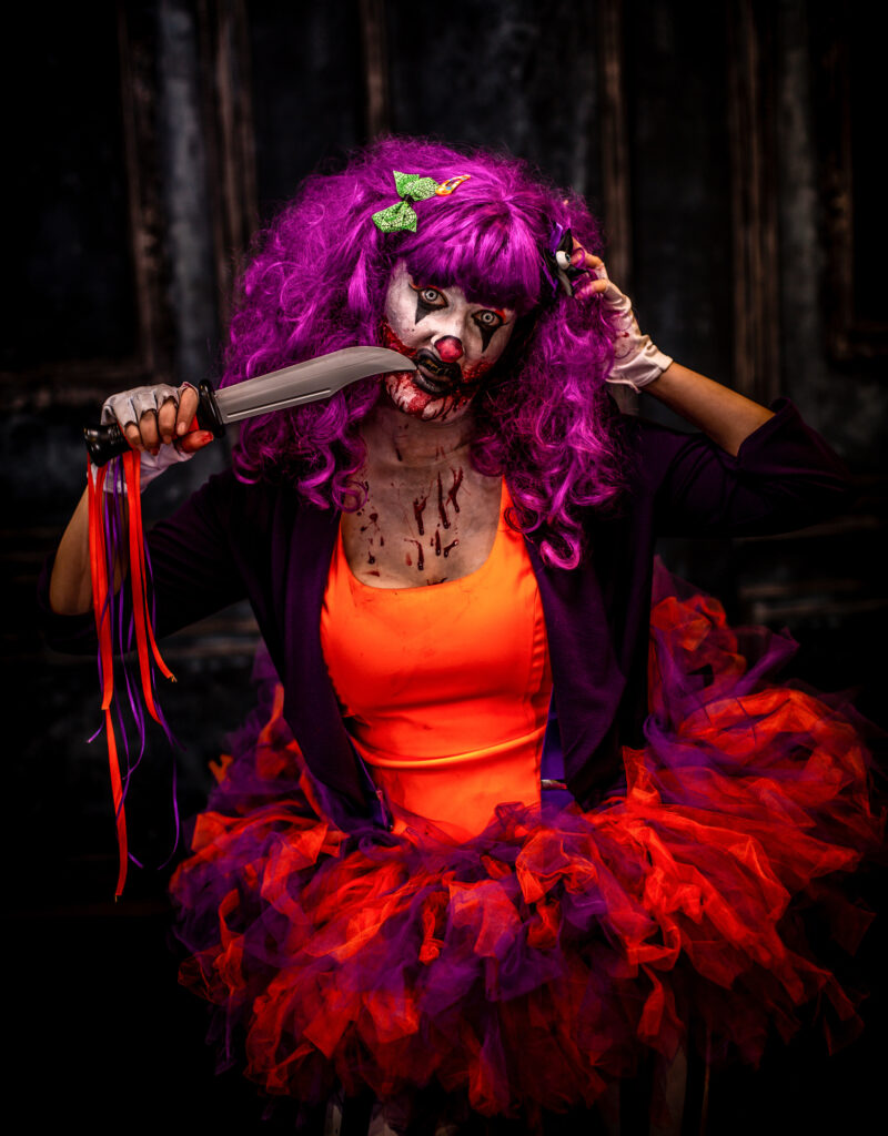 Pink-haired horror character with theatrical makeup, glowing colors and red clawed hands.