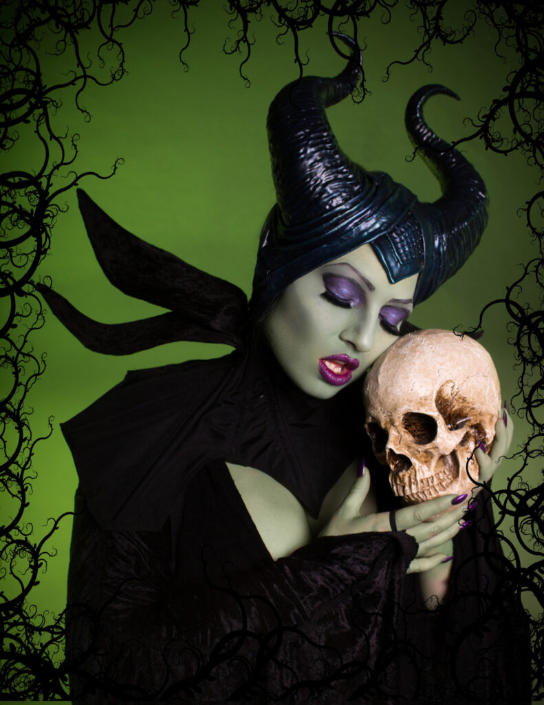 Green-skinned horned sorceress holding a skull against a twisted woodland background.