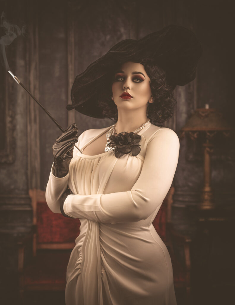 Woman in an ivory vintage dress with a black floral necklace in a shadowy room.